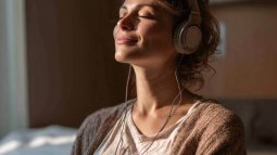 Mujer embarazada escuchando música con auriculares durante el embarazo para relajarse antes del parto.