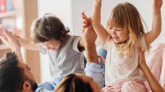 niños con padres jugando en la cama