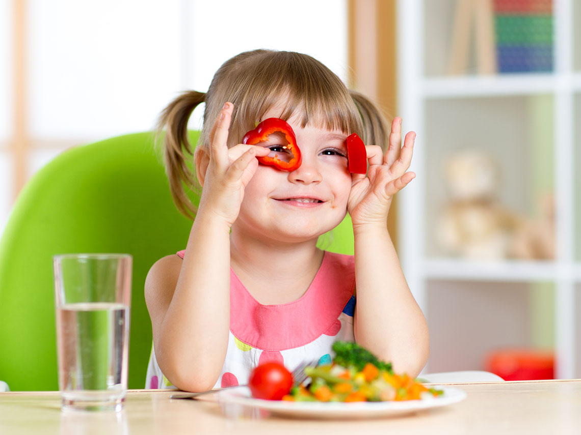 niña jugando con las verduras