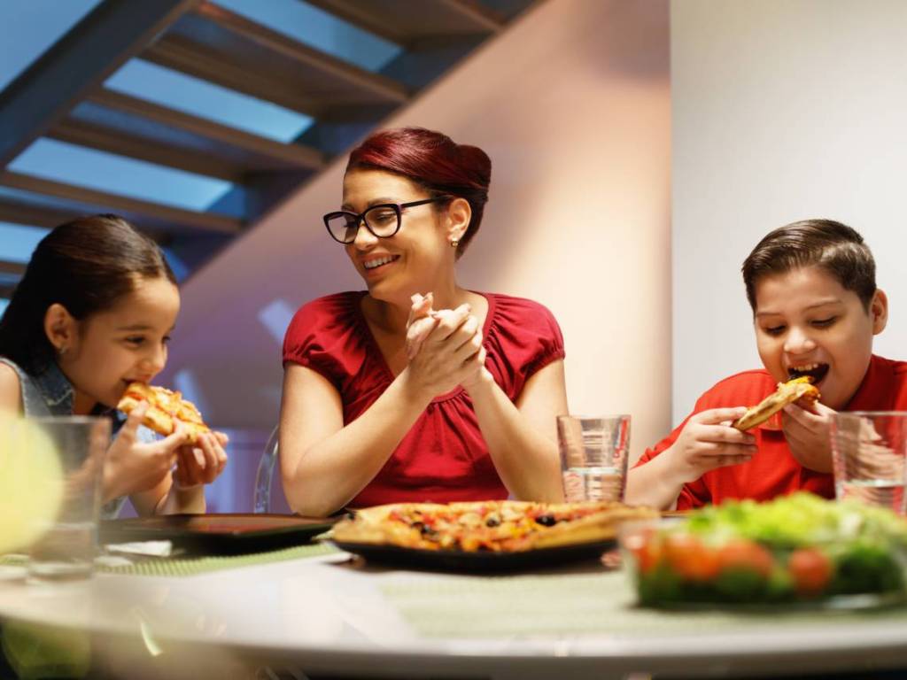 Familia cenando pizza y ensalada