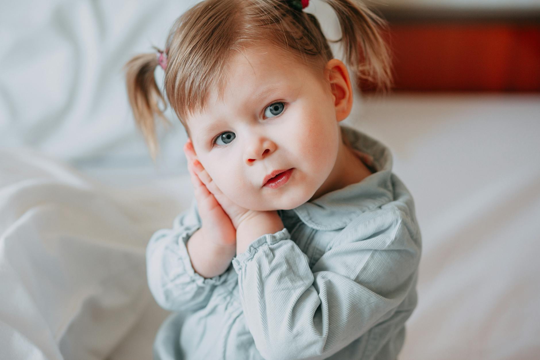 baby with both hands on right cheek