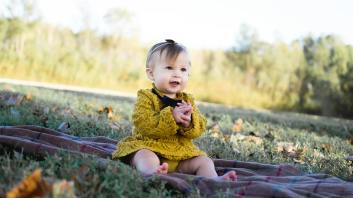 baby wearing yellow crochet long sleeve dress sitting on brown textile