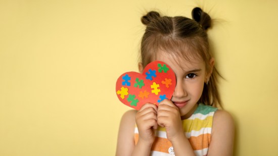 Niña con el corazón del rompecabezas del Autismo