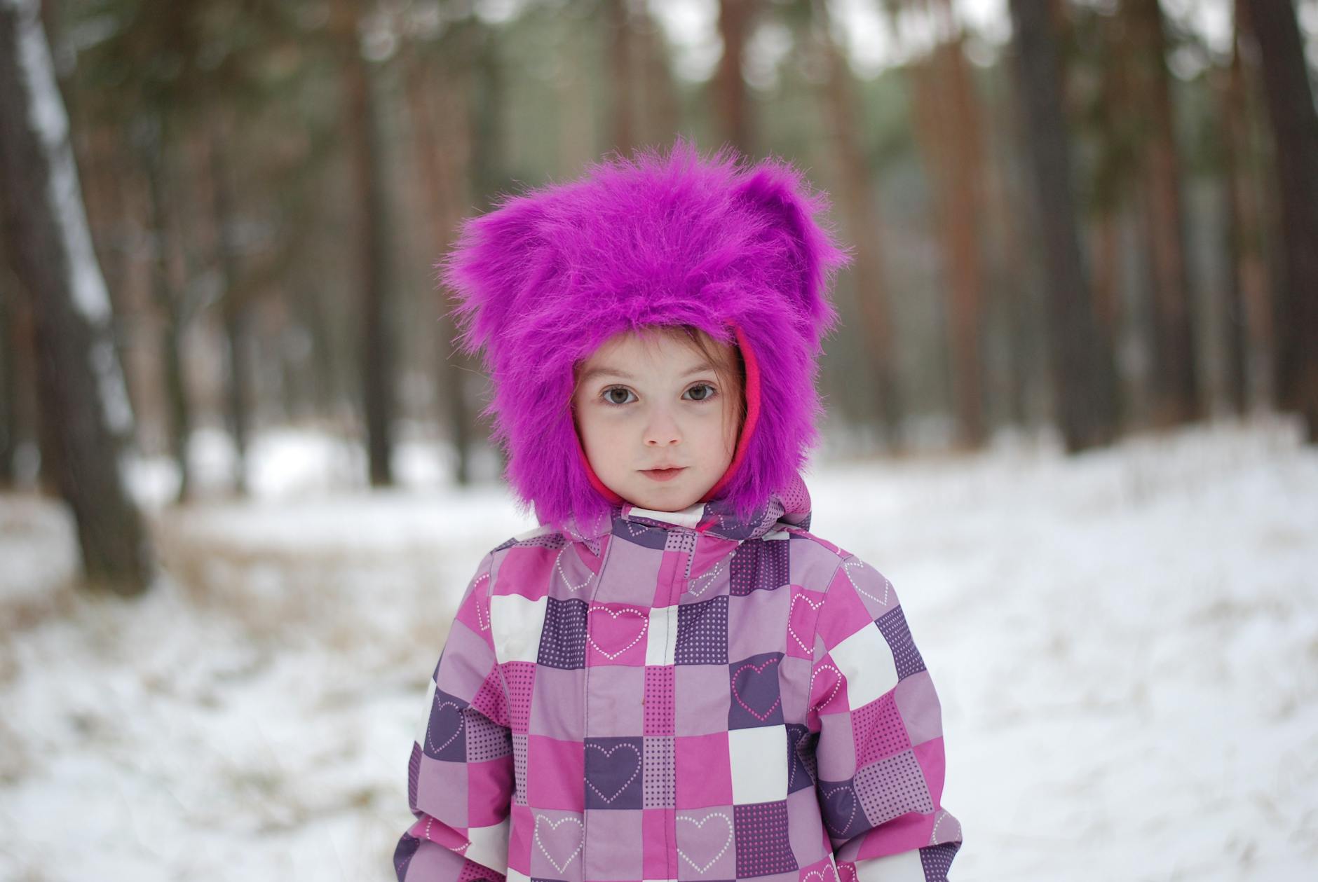 Una niña con una abrigo morado en la nieve
