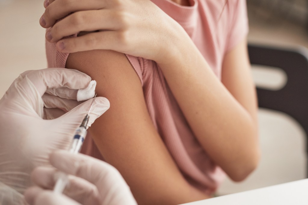 Un proesional poniendo una vacuna en el brazo
