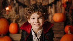 Niño con disfraz casero de vampiro hecho con materiales reciclados y decorado con calabazas de Halloween.