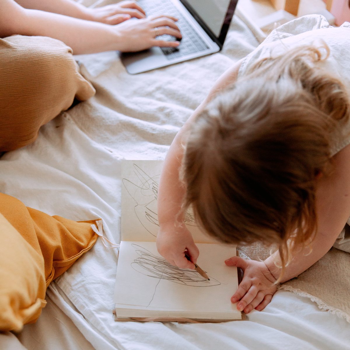 Niña coloreando mientras su madre trabaja a su lado