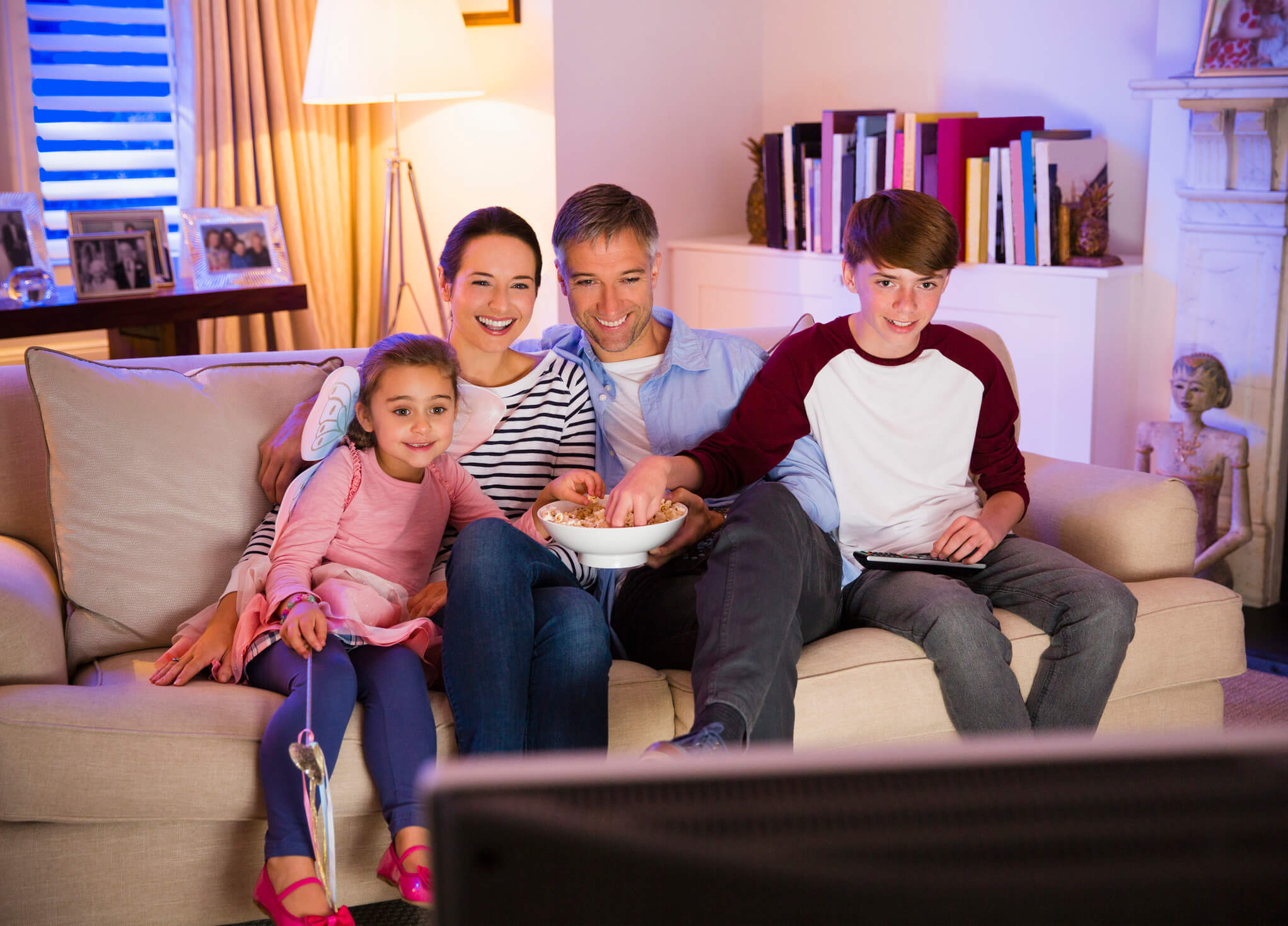 Familia comiendo palomitas y viendo la televisión