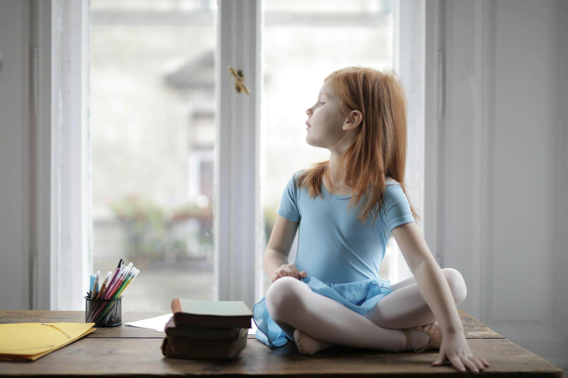 Niña mirando distraídamente por la ventana