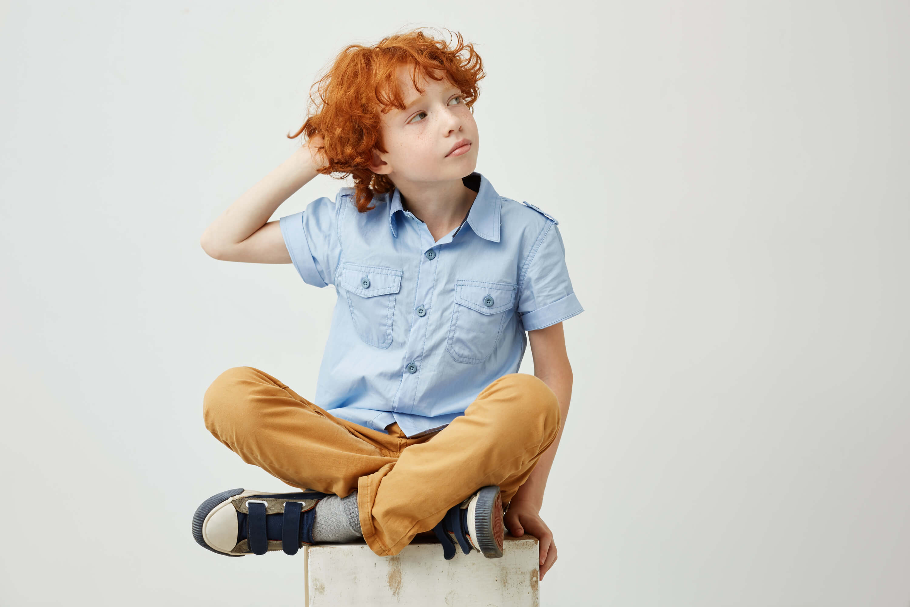 beautiful-ginger-boy-with-curly-hair-freckles-casual-clothes-holding-hand-head-looking-aside-with-relaxed-expression