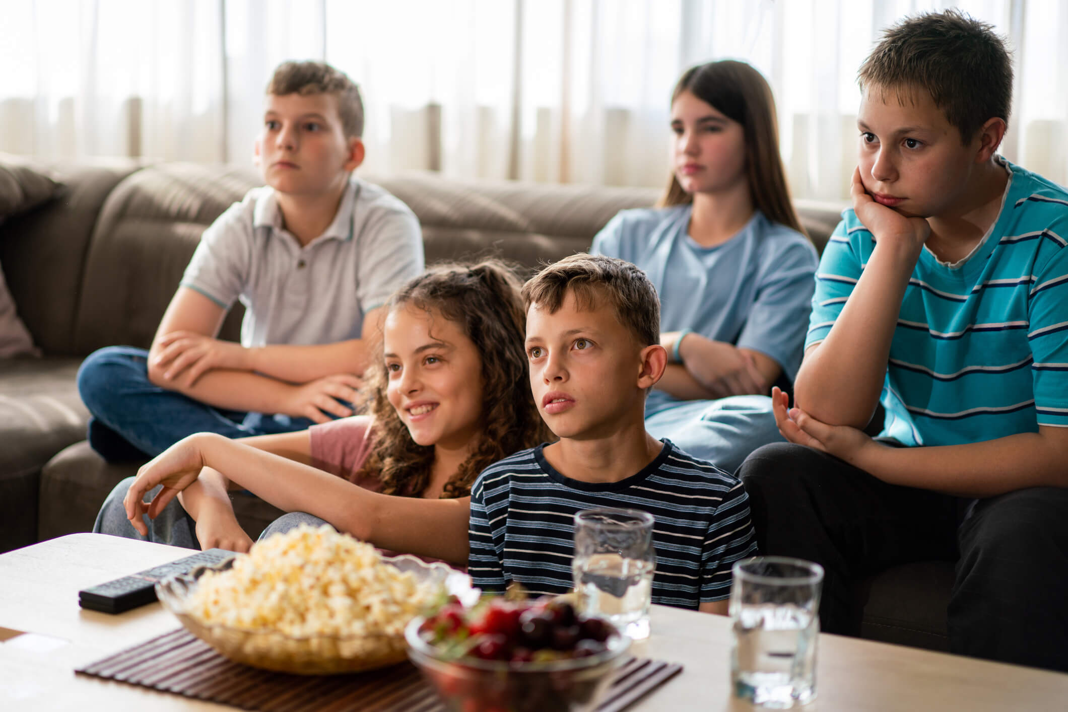 Grupo de adolescentes come ultraprocesados viendo la tele