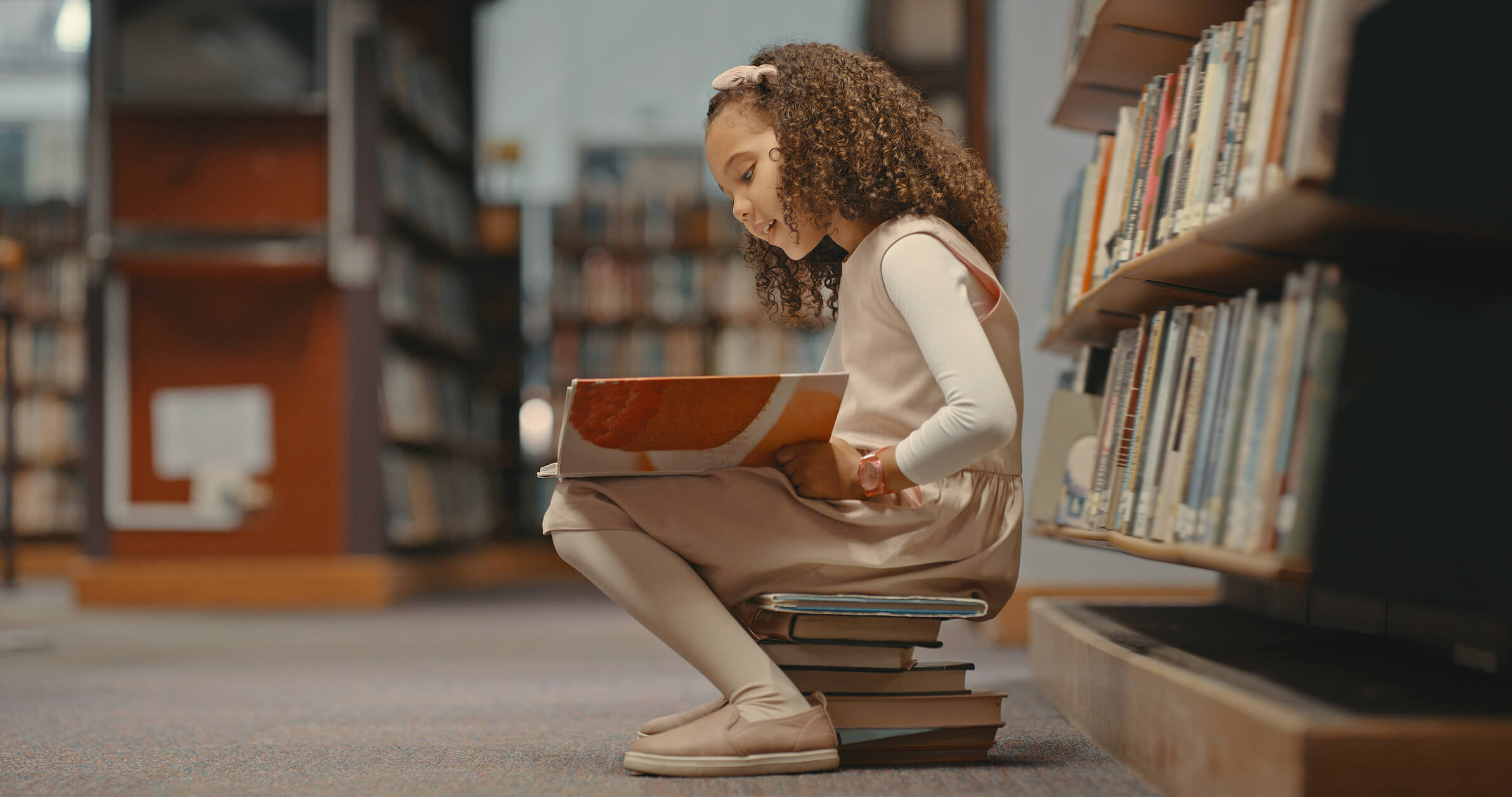Una niña, leyendo en la biblioteca