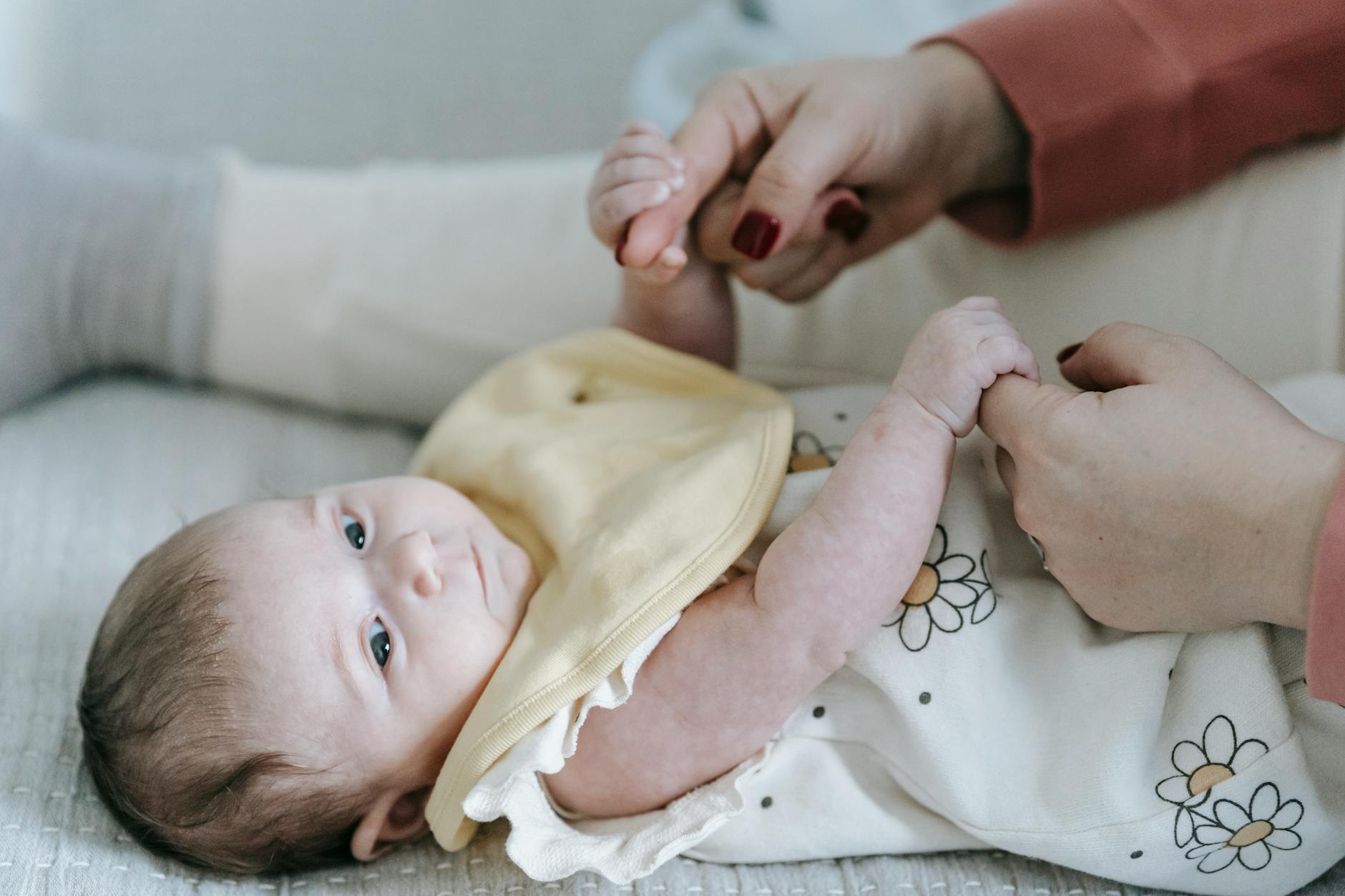 crop mom holding caressing cute infant on changing table