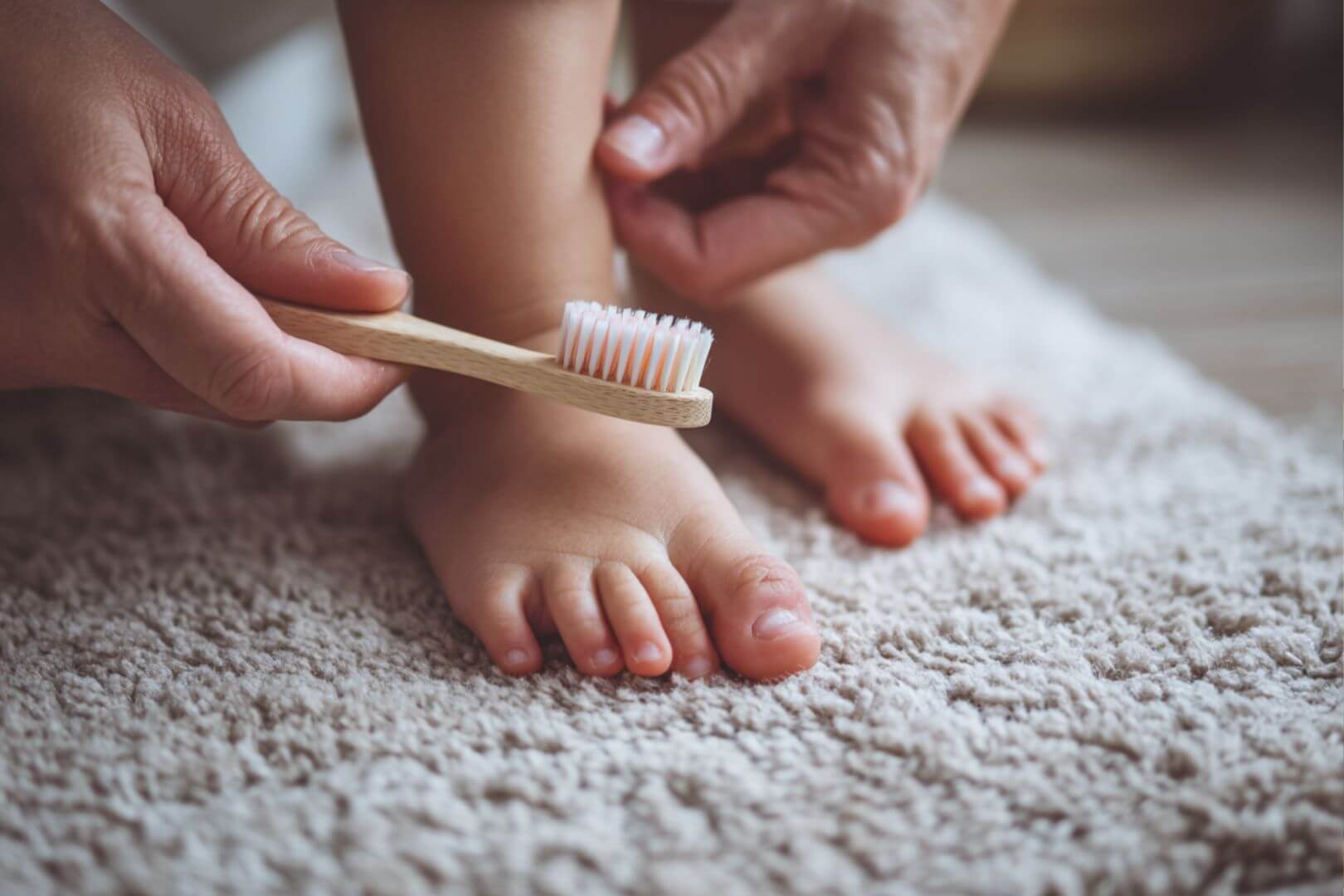 Un adulto limpia con cuidado las uñas de los pies de un niño utilizando un cepillo suave: higiene y mimo en la rutina diaria