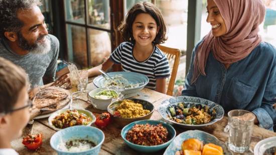 Familia reunida en la mesa disfrutando de un almuerzo saludable con platos tradicionales y nutritivos.