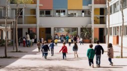 Fachada de un colegio con niños y niñas accediendo al patio y a las aulas.