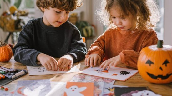 Niños haciendo actividades imprimibles de Halloween vocabulary en inglés con dibujos de fantasmas y calabazas sobre la mesa.