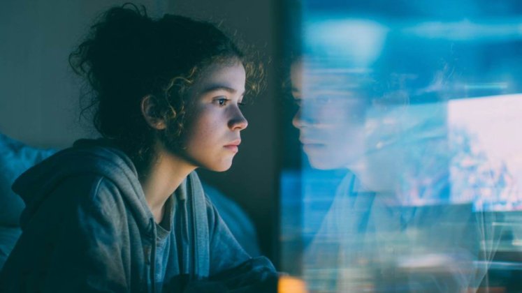 Adolescente frente a dos pantallas: una activa y otra pasiva, símbolo del impacto distinto del uso digital en el cerebro.