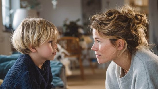 Madre y niño se miran con calma en casa, mostrando una conversación respetuosa tras un error.
