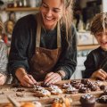Familia preparando dulces caseros de Halloween con niños, decorando galletas y cupcakes con motivos de calabazas y fantasmas en una cocina otoñal.