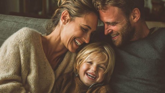 Padres e hijo riendo juntos en casa, símbolo de conexión emocional y crianza consciente.