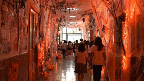 Pasillo de un colegio transformado en casa del terror con niños disfrazados y decoración de Halloween.