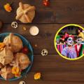 Pan de muerto tradicional decorado con flores de cempasúchil sobre una mesa de madera, junto a niños con el rostro pintado de calaveras durante la celebración del Día de Muertos.
