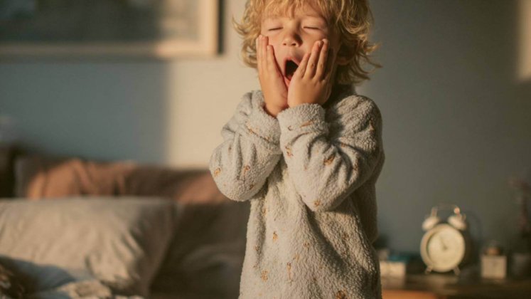 Niño bostezando en su habitación al amanecer tras el cambio de hora en España.